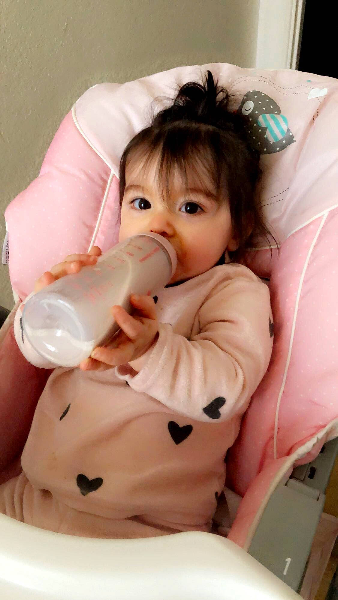 Ylona a rejoint le concours — aidez-le/la à gagner de superbes lots ! baby_toddler_clothing, cheek, chin, comfort, drinkware, eyelash, finger, hand, head, human_body, mouth, neck, nose, person, pink, plastic_bottle, skin, sleeve, textile, toddler