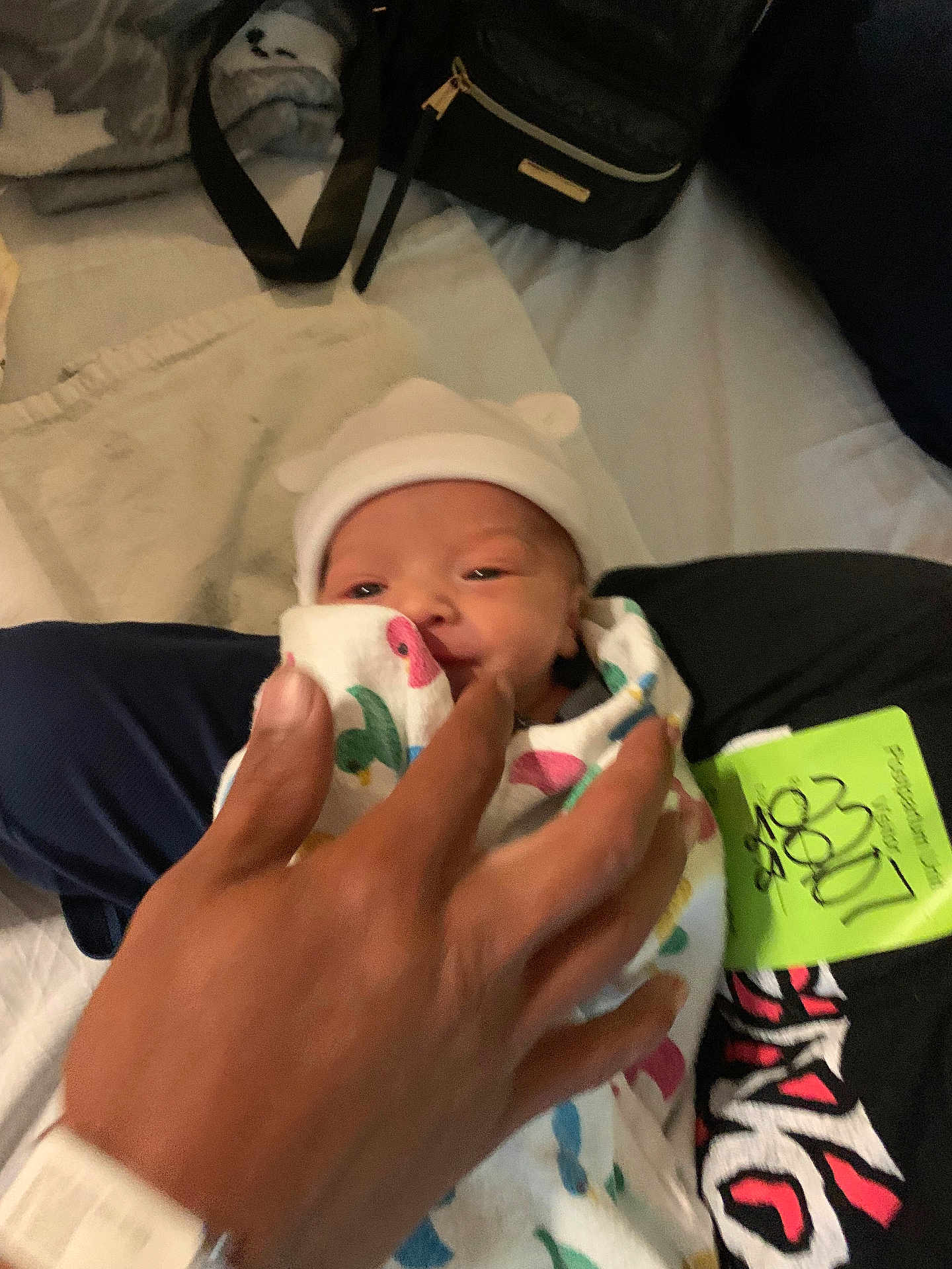 Jonathan is registered to the contest to win money with this photo: newborn, baby, swaddle, hat, hand, bed, blanket, person, infant, cute, sleepwear, resting, indoor, soft, human, clothing, tender, closeup, family, comfort