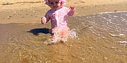 Layla is registered to the contest to win money with this photo: baby, child, beach, water, splashing, swimsuit, sun_hat, sand, sea, waves, outdoor, summer, nature, sky, trees, holiday, vacation, sunny, play, fun