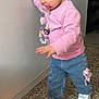 toddler, child, pacifier, pacifier_clip, hair_bows, butterfly_beads, pink_sweatshirt, jeans, white_sneakers, standing, indoor, wall, hand_on_wall, terrazzo_floor, portrait, walking, cute, baby_accessory, short_hair, concentration