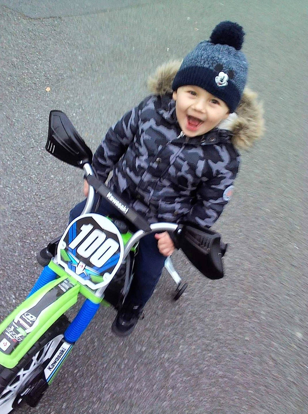 Noé participe au concours pour gagner de l'argent avec cette photo : asphalt, automotive_design, automotive_tire, automotive_wheel_system, bicycle_accessory, cap, electric_blue, fender, headwear, motor_vehicle, person, personal_protective_equipment, recreation, rim, rolling, shoe, smile, sneakers, tire, toddler