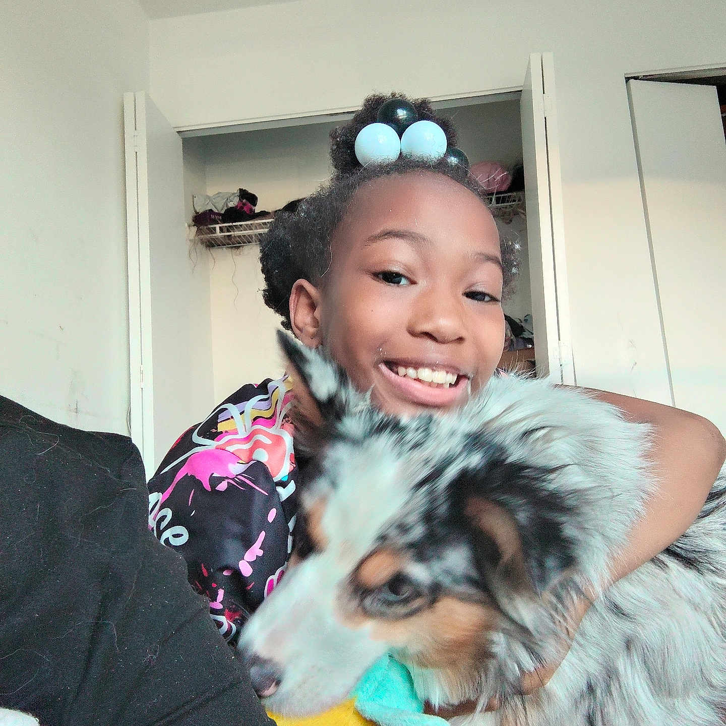 Princess Lily is registered to the contest to win money with this photo: child, dog, smiling, indoor, toy, hair_beads, clothing, face, pet, hugging, furniture, casual, portrait, multicolor, animal, happy, cozy, home, young, friendship