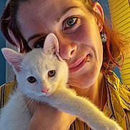 Roxie joined the competition — help win amazing prizes! affection, animal, cat, closeup, cute, earring, face, feline, hand, indoor, kitten, person, pet, piercing, portrait, smile, striped_shirt, warm_lighting, white_cat, yellow_shirt