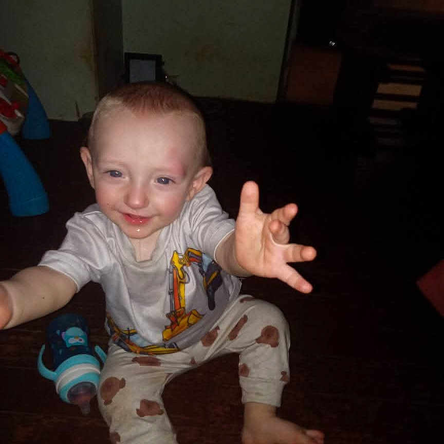 Braxton joined the competition — help win amazing prizes! baby, child, clothing, face, floor, happy, home, indoor, pants, person, playful, reaching, shirt, sippy_cup, sitting, smiling, toddler, toy, wooden_floor, young