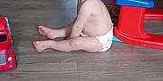 Braxton is registered to the contest to win money with this photo: toddler, child, diaper, floor, toy, plastic, play_table, red, blue, curious, indoor, wooden_floor, person, baby, sitting, looking_back, playtime, colorful, home, young_child