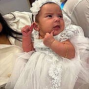 Hannah is registered to the contest to win money with this photo: baby, bracelet, celebration, child, closeup, clothing, cute, expression, face, family, fashion, headband, holding, indoor, infant, lace, person, portrait, soft_light, white_dress