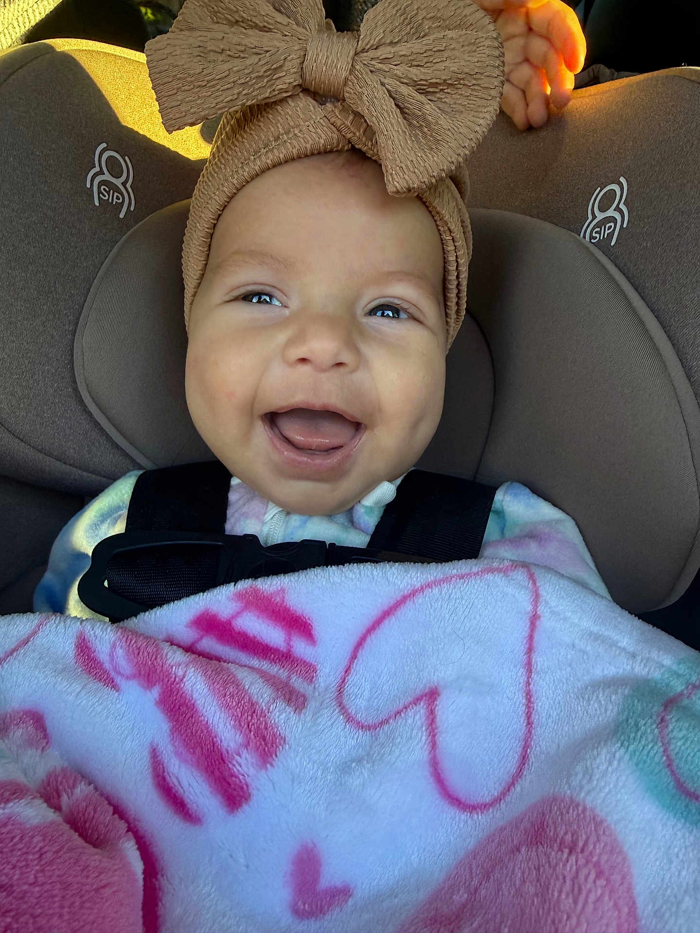 Mackenzie joined the competition — help win amazing prizes! baby, smiling, car_seat, headband, bow, blanket, heart_pattern, child, happy, infant, closeup, face, person, seatbelt, cute, indoors, toddler, apparel, childhood, portrait