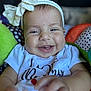 baby, child, smiling, headband, bow, white_shirt, reaching, hand, face, happy, indoor, cushion, colorful, closeup, infant, cute, portrait, baby_toy, soft_toys, playful