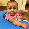 baby, child, infant, pink_clothing, blue_cushion, face, indoor, wood_floor, curious, seated, person, arm, expression, furniture, young, cute, looking_at_camera, portrait, skin, head