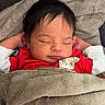 baby, sleeping, blanket, red_clothing, cat_illustration, couch, cozy, resting, infant, peaceful, indoors, soft_texture, child, portrait, cute, relaxed, young, wrapped, head, closed_eyes
