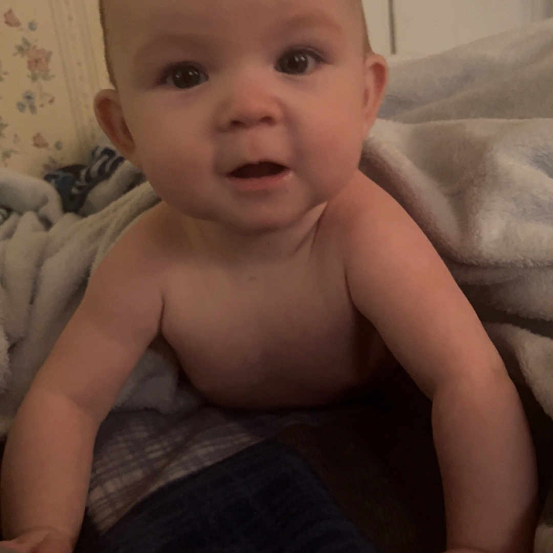 Layla is registered to the contest to win money with this photo: baby, bedding, bedroom, blanket, cheeks, child, closeup, crawling, cute, eyes, hands, home, indoor, infant, looking_at_camera, portrait, skin, smile, towel, wallpaper