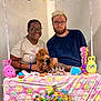 Sir Edward is registered to the contest to win money with this photo: person, dog, glasses, table, easter, decoration, wreath, bunny, colorful, party, smile, celebration, indoor, festive, curly_hair, beard, tshirt, ornament, ribbon, happy