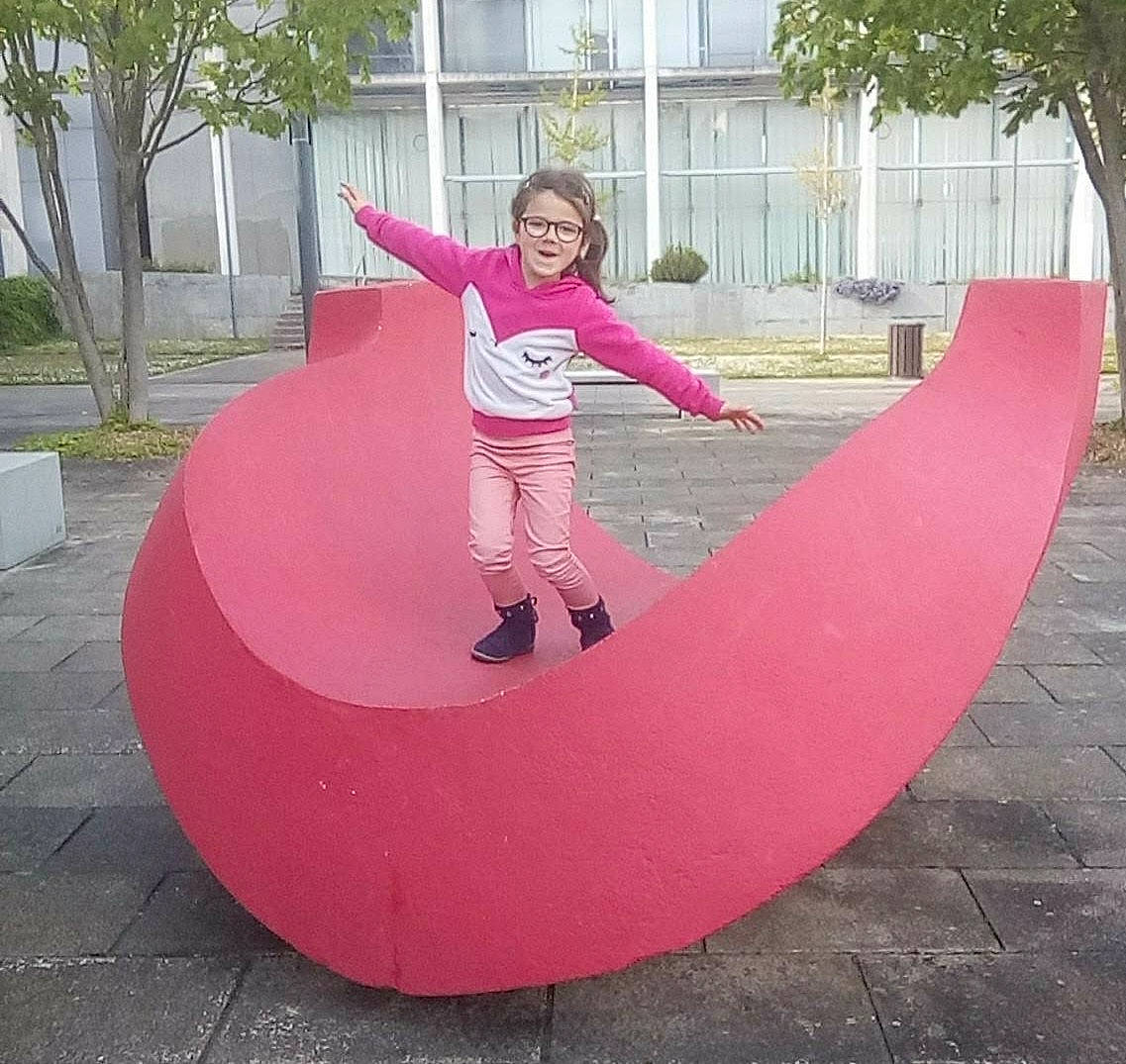 Agathe a rejoint le concours — aidez-le/la à gagner de superbes lots ! art, balance, circle, city, fun, grass, leisure, magenta, outdoor_play_equipment, people_in_nature, person, pink, plant, public_space, recreation, smile, symmetry, tints_and_shades, toddler, tree