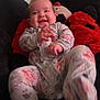 Lakelynn is registered to the contest to win money with this photo: baby, smiling, pajamas, floral_pattern, couch, plush_pillow, red, black, happy, infant, hand, foot, indoors, person, child, face, cozy, relaxed, seated, cute