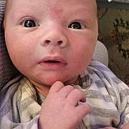 Trevor is registered to the contest to win money with this photo: baby, infant, close_up, face, hand, striped_clothing, onesie, curious, wide_eyes, indoor, person, newborn, skin, expression, baby_clothes, human, child, portrait, holding_hand, casual