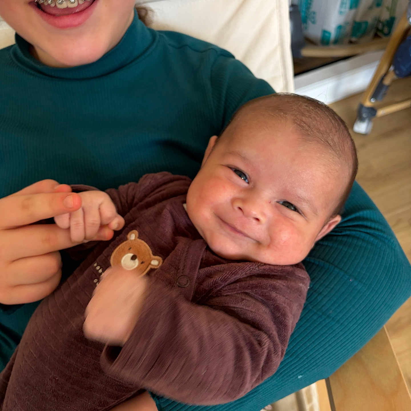 Zayaan participe au concours pour gagner de l'argent avec cette photo : baby, child, smile, braces, holding, teddy_bear_patch, brown_outfit, teal_top, hand_holding, indoor, happy, face, person, furniture, chair, floor, wooden_floor, couch, plush_toy, diapers