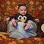 baby, child, costume, duck, brown_clothing, headband, blanket, autumn, fall_leaves, decorations, pumpkins, corn, woven_pumpkins, smile, portrait, indoor, seasonal, cute, sitting, cozy