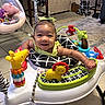baby, infant, smiling, activity_walker, toy, indoor, child, play, face, clothing, floor, furniture, bouncer, peppa_pig, bow, happy, colorful, person, portrait, toddler