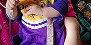 Destinee is registered to the contest to win money with this photo: baby, blanket, cheerful, child, closeup, curly_hair, cute, expression, face, hand, holding, indoor, infant, leggings, person, portrait, purple_clothing, ring, sitting, yellow_clothing