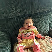 Destinee is registered to the contest to win money with this photo: baby, child, smiling, sitting, couch, clothing, happy, infant, person, indoors, cute, pattern, fabric, foot, hand, face, home, portrait, cozy, colorful