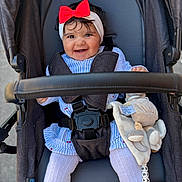 Neïssa a rejoint le concours — aidez-le/la à gagner de superbes lots ! baby, child, smile, stroller, red_bow, headband, plush_toy, straps, clothing, white_tights, happy, outdoor, person, cute, infant, seat, blue_stripes, toy, safety_buckle, portrait