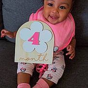 Journee joined the competition — help win amazing prizes! baby, child, smiling, pink_socks, pink_bib, minnie_mouse_leggings, hair_bows, wooden_sign, flower, number_4, couch, indoor, cute, happy, portrait, sitting, infant, clothing, person, celebration