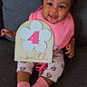 baby, child, smiling, pink_socks, pink_bib, minnie_mouse_leggings, hair_bows, wooden_sign, flower, number_4, couch, indoor, cute, happy, portrait, sitting, infant, clothing, person, celebration