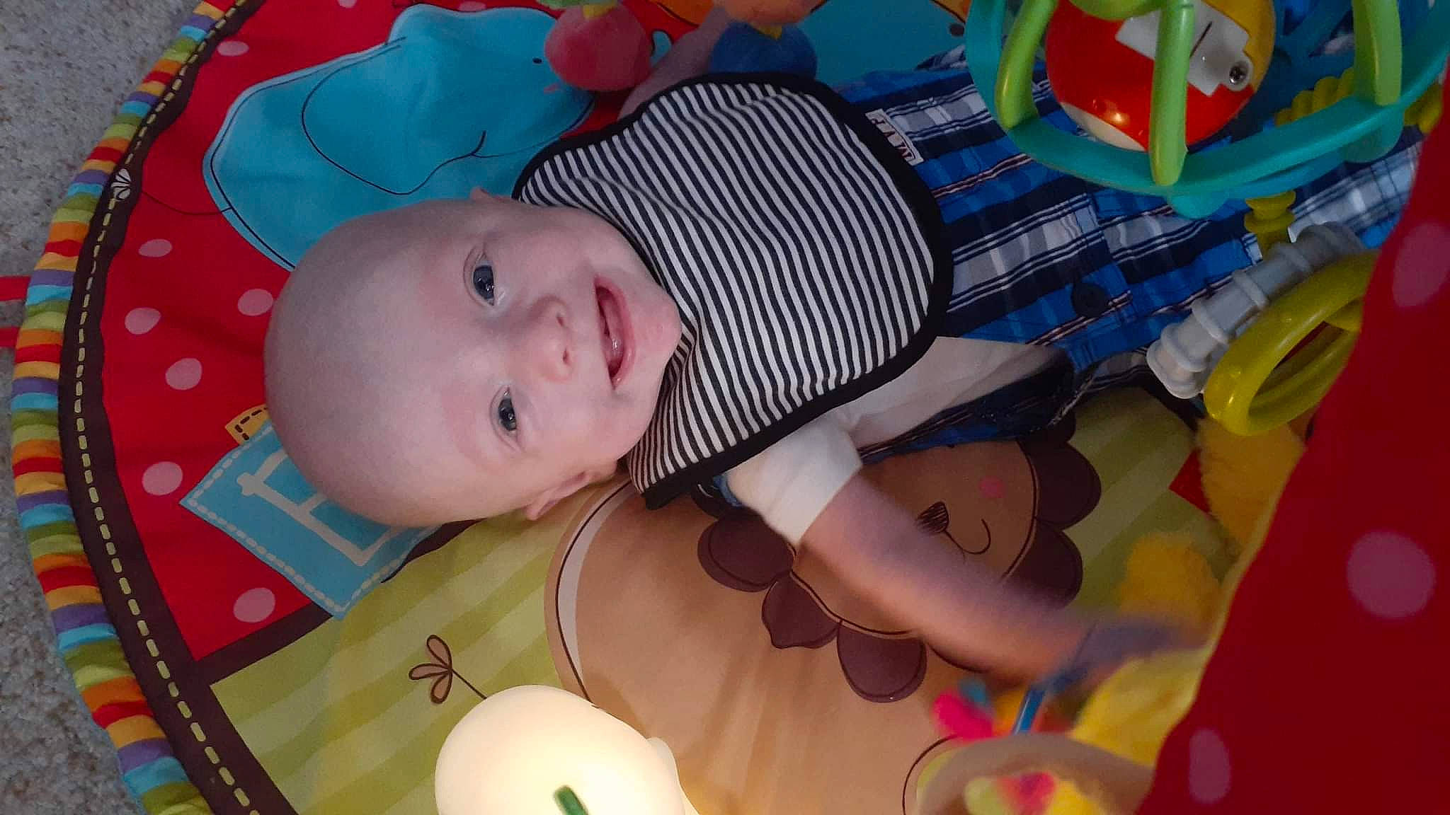 Greyson is registered to the contest to win money with this photo: baby, baby_products, baby_safety, baby_toddler_clothing, baby_toys, cheek, child, circle, comfort, facial_expression, fun, infant_bed, iris, linens, pattern, person, room, skin, smile, toddler