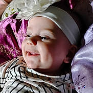 Maliza is registered to the contest to win money with this photo: baby, baby_girl, child, closeup, cushion, cute, embroidery, face, flower, happy, headband, indoors, infant, joyful, person, portrait, purple_cushion, smiling, soft_lighting, striped_clothing