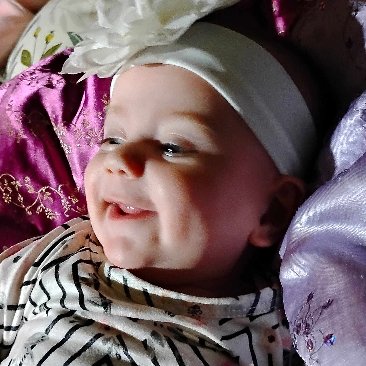 Maliza is registered to the contest to win money with this photo: baby, baby_girl, child, closeup, cushion, cute, embroidery, face, flower, happy, headband, indoors, infant, joyful, person, portrait, purple_cushion, smiling, soft_lighting, striped_clothing