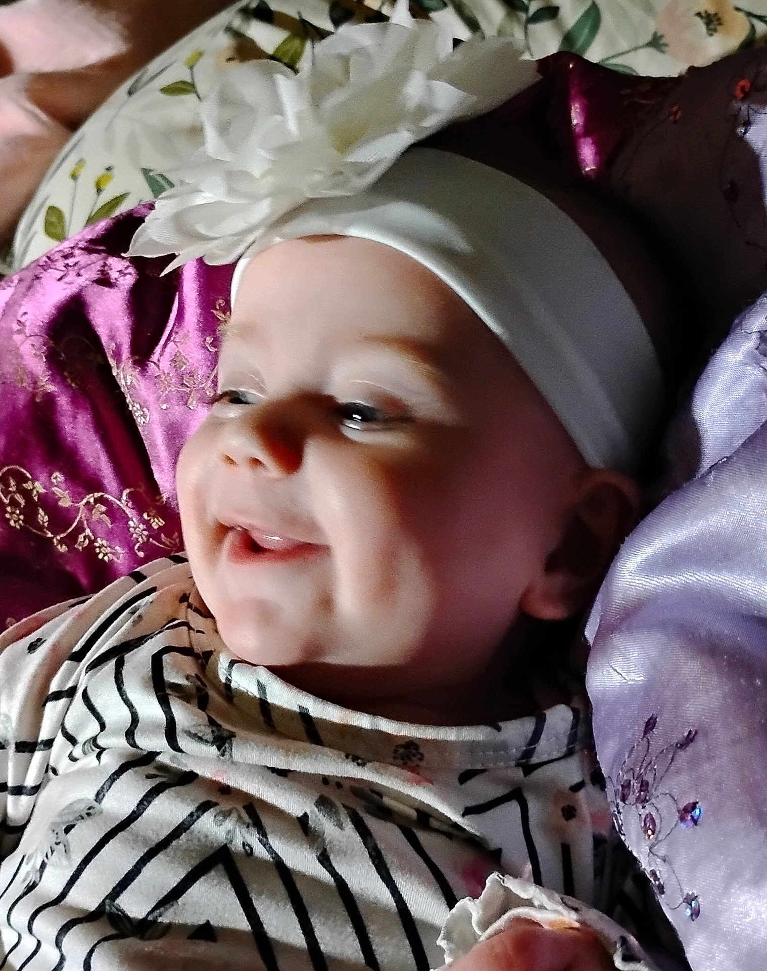 Maliza is registered to the contest to win money with this photo: baby, baby_girl, child, closeup, cushion, cute, embroidery, face, flower, happy, headband, indoors, infant, joyful, person, portrait, purple_cushion, smiling, soft_lighting, striped_clothing