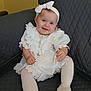baby, child, smiling, white_dress, headband, blue_eyes, sitting, couch, indoor, portrait, cute, happy, tights, shoes, jewelry, infant, person, fashion, accessory, young