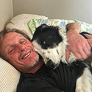 Bailey joined the competition — help win amazing prizes! animal, bed, black_and_white_dog, blanket, casual, closeup, comfort, cuddle, dog, friendship, happy, hug, human, indoor, man, pet, pillow, relaxed, resting, smile