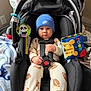 baby, infant, car_seat, blue_hat, nike, onesie, football_pattern, toy, blanket, safety_harness, child, indoor, cute, serious_expression, plush_toy, colorful, seat, holding, young_child, portrait