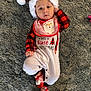 baby, infant, christmas, holiday, santa_hat, bib, onesie, red, white, striped_socks, carpet, floor, cute, festive, smiling, lying_down, child, person, indoors, cozy
