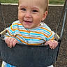 toddler, child, swing, playground, outdoor, happy, smiling, clothing, striped_shirt, blue_pants, blanket, play, fun, baby, park, metal_swing, grass, fence, daylight, cute