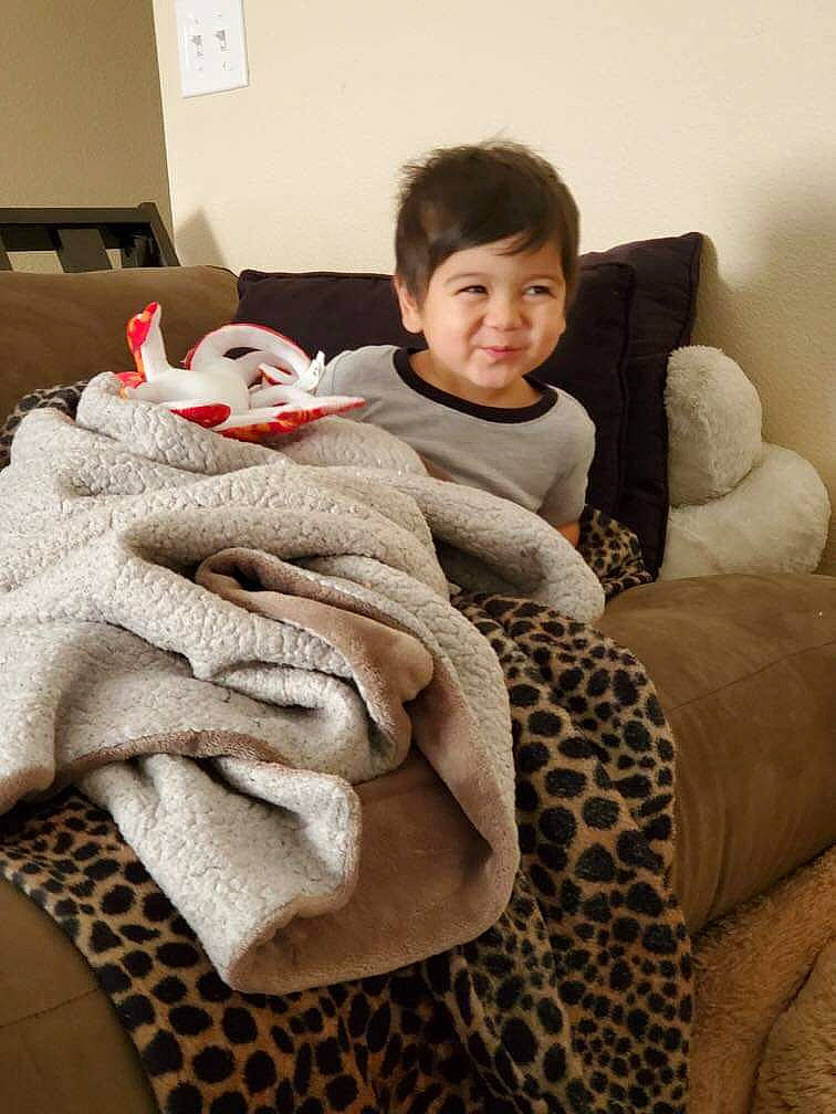 Ezra is registered to the contest to win money with this photo: baby, blanket, child, comfort, fur, furniture, linens, person, room, skin, textile, toddler