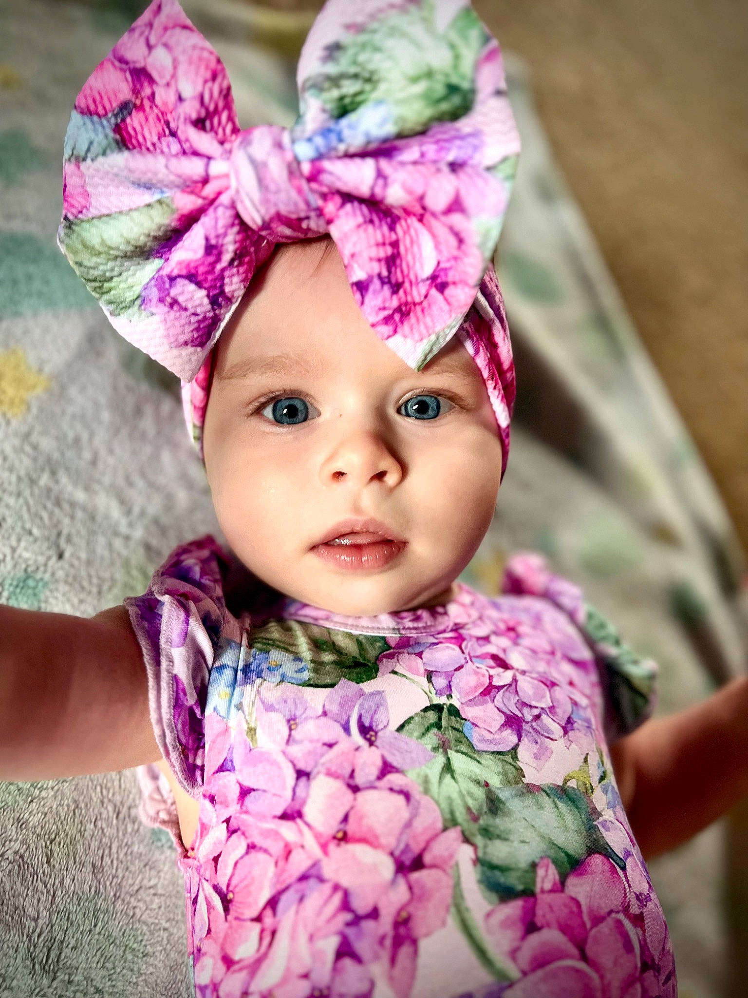Miriam joined the competition — help win amazing prizes! baby, baby_toddler_clothing, cap, child, costume_hat, face, fashion_accessory, grass, hair_accessory, happy, headband, headgear, headpiece, headwear, magenta, pattern, person, pink, purple, sleeve