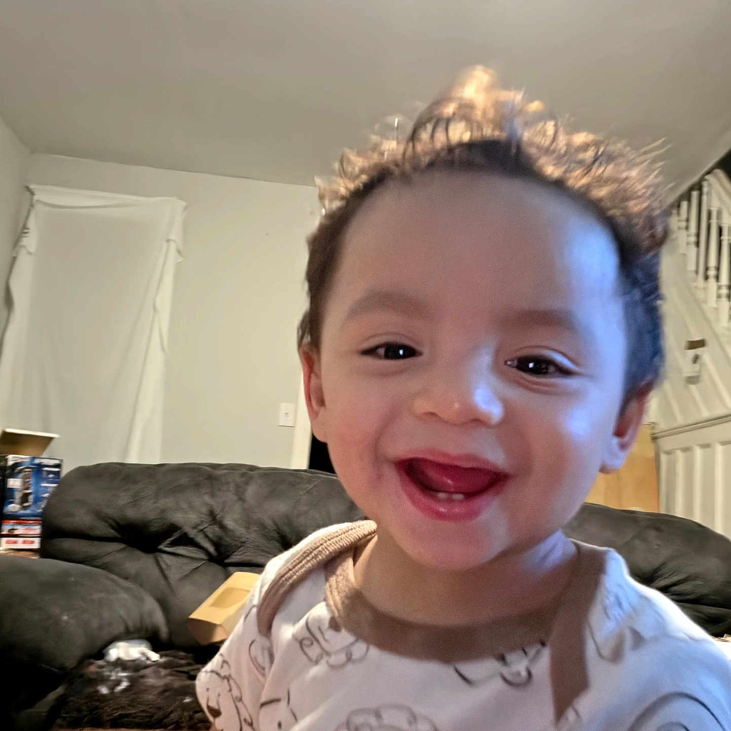 Leonardo joined the competition — help win amazing prizes! toddler, child, smile, happy, indoor, couch, sofa, onesie, animal_print, curly_hair, face, person, living_room, staircase, window, blanket, cozy, cute, furniture, home