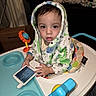 Leonardo joined the competition — help win amazing prizes! toddler, child, baby_walker, hooded_towel, remote_control, indoor, toy, face, person, furniture, blanket, clothing, curious, expression, seated, colorful, household_items, cardboard_box, living_room, young_child