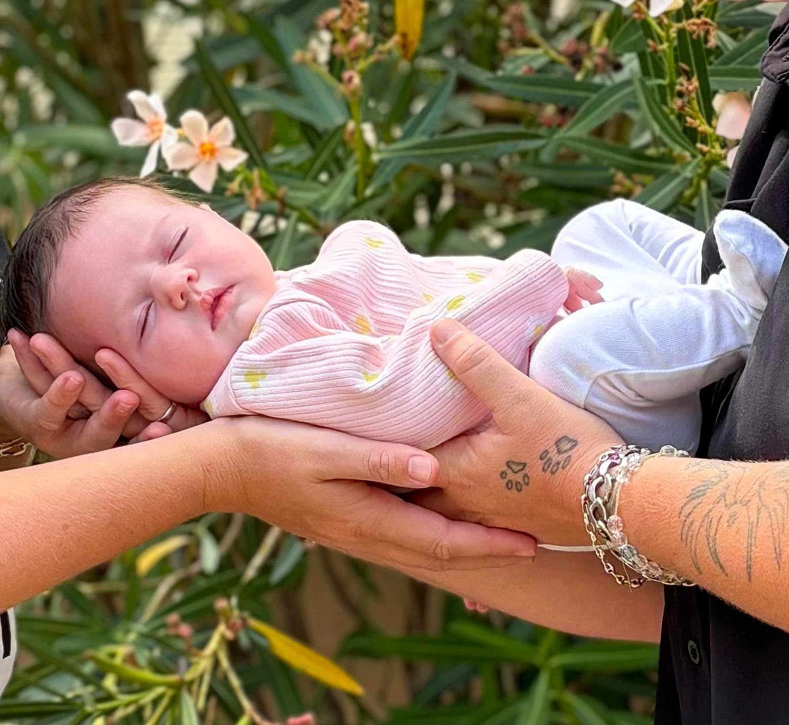 Ilohé a rejoint le concours — aidez-le/la à gagner de superbes lots ! baby, sleeping, hands, tattoo, bracelet, pink_clothing, white_pants, flower, greenery, outdoor, person, infant, peaceful, nature, portrait, closeup, skin, rest, cute, tenderness