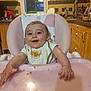 baby, high_chair, messy, food, kitchen, bib, smiling, child, infant, face, hands, window, cabinet, countertop, sink, utensils, light, person, happy, meal_time