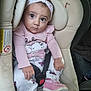 baby, child, car_seat, pink_clothing, headband, shoes, seatbelt, indoors, cute, portrait, infant, sitting, looking_at_camera, expression, small_hands, footwear, car_interior, fabric, comfort, safety