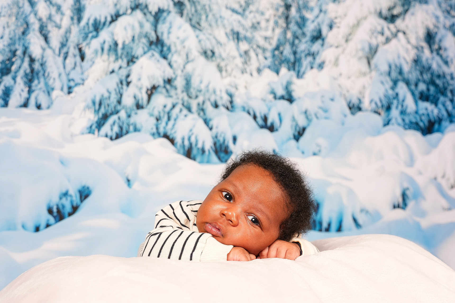 Isayah a rejoint le concours — aidez-le/la à gagner de superbes lots ! baby, infant, newborn, portrait, face, eyes, cheeks, hands, striped_shirt, blanket, bedding, snow, winter_scene, snowy_backdrop, evergreen_trees, studio_photo, cozy, adorable, laying_down, curly_hair