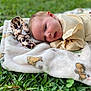 April is registered to the contest to win money with this photo: baby, infant, blanket, outdoor, grass, face, head, person, smiling, happy, clothing, nature, cute, lying_down, animal_pattern, soft_texture, child, young, closeup, skin
