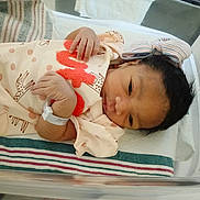 Za'Liyah is registered to the contest to win money with this photo: newborn, baby, infant, child, face, eyes_open, hospital, bassinet, blanket, swaddle, knitted_cap, clothing, onesie, giraffe_pattern, wristband, lying_down, portrait, indoors, bedding, adorable