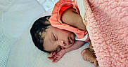 Za'Liyah is registered to the contest to win money with this photo: baby, bed, bedding, closed_eyes, cozy, curled_up, dark_hair, face, indoors, infant, newborn, orange_clothing, peaceful, photography, pink_blanket, portrait, resting, sleeping, soft_blanket, white_surface