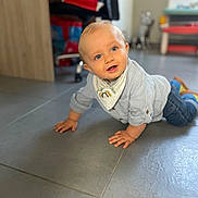 Aksel a rejoint le concours — aidez-le/la à gagner de superbes lots ! baby, child, crawling, floor, indoor, blue_eyes, shirt, jeans, bib, shoes, tiled_floor, home, furniture, blurred_background, person, cute, smiling, hands, head, portrait