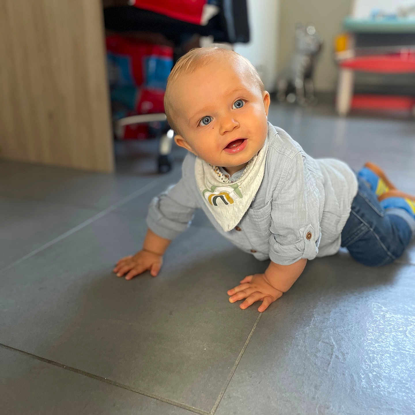 Aksel a rejoint le concours — aidez-le/la à gagner de superbes lots ! baby, bib, blue_eyes, blurred_background, child, crawling, cute, floor, furniture, hands, head, home, indoor, jeans, person, portrait, shirt, shoes, smiling, tiled_floor
