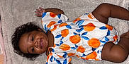 Adore joined the competition — help win amazing prizes! baby, child, infant, smiling, curly_hair, blanket, orange_pattern, blue_leaves, clothing, lying_down, cute, happy, portrait, soft_texture, skin, person, toddler, indoors, colorful, fabric